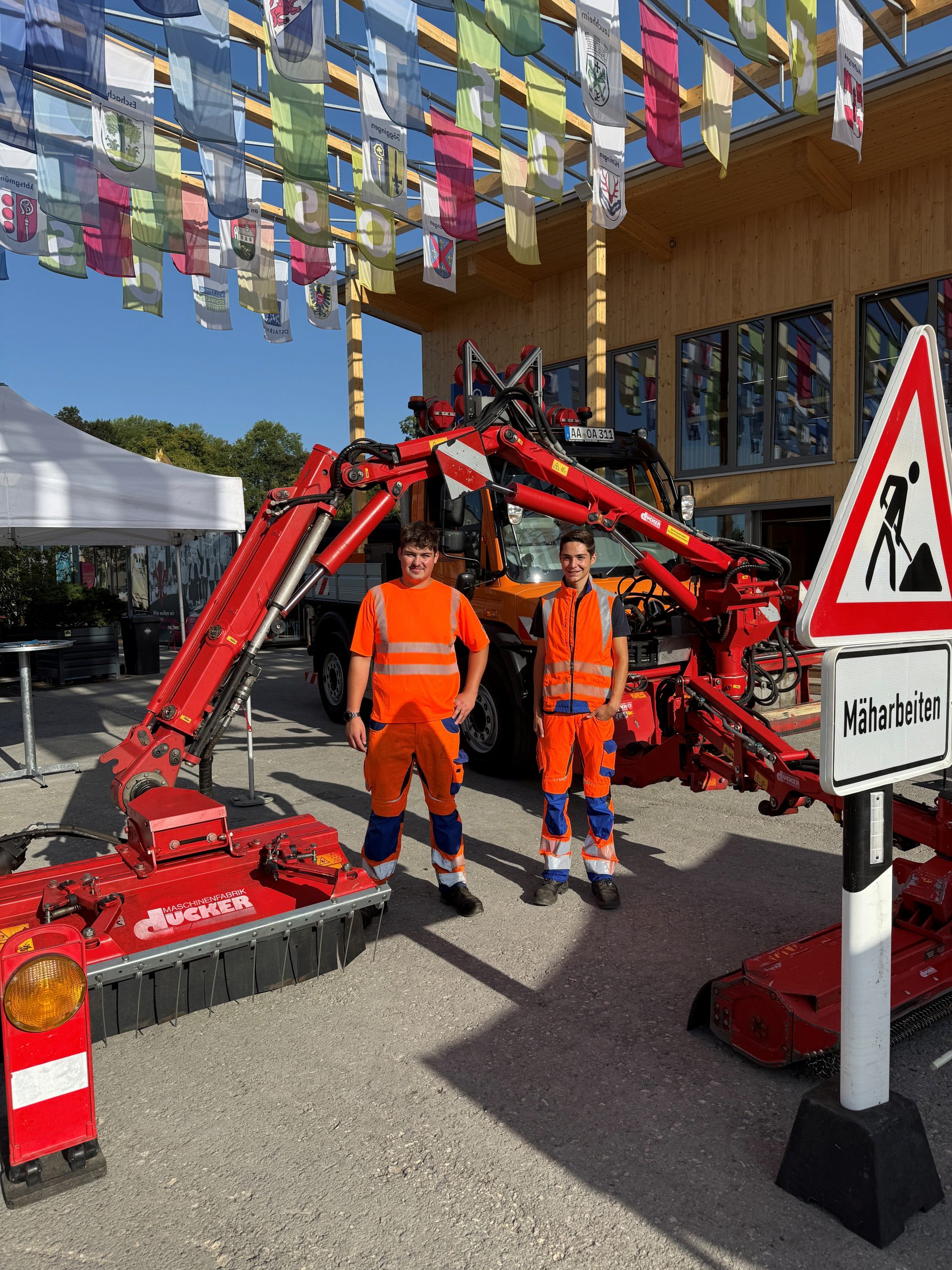 Die Straßenwärter Maximilian Klos und Noah Wagner vor einem Arbeitsfahrzeug des Ostalbkreises.
